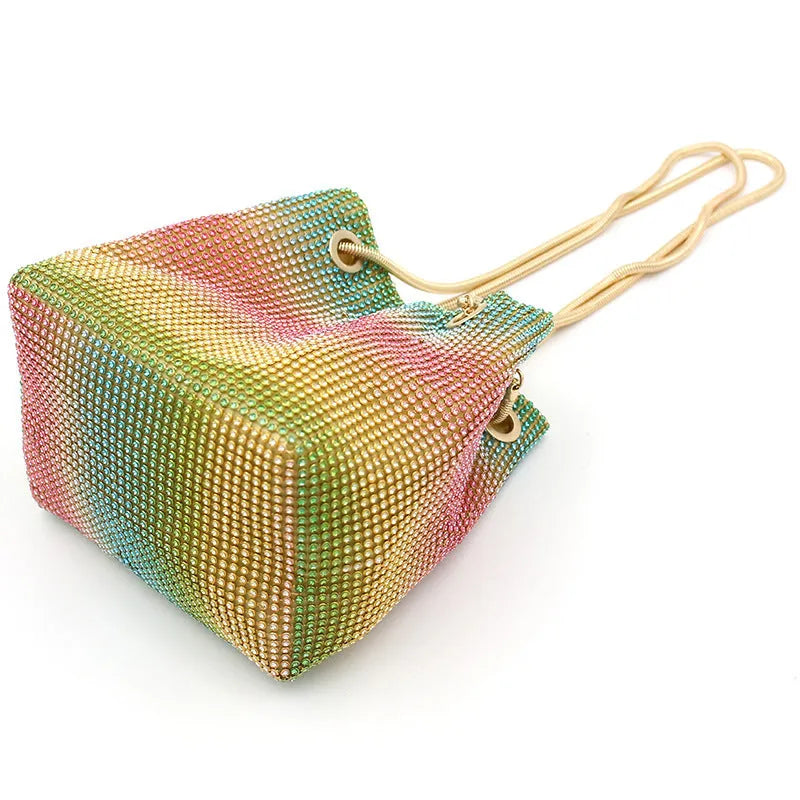 Rainbow coloured rhinestone bucket bag with a crossbody shoulder strap on a white background.