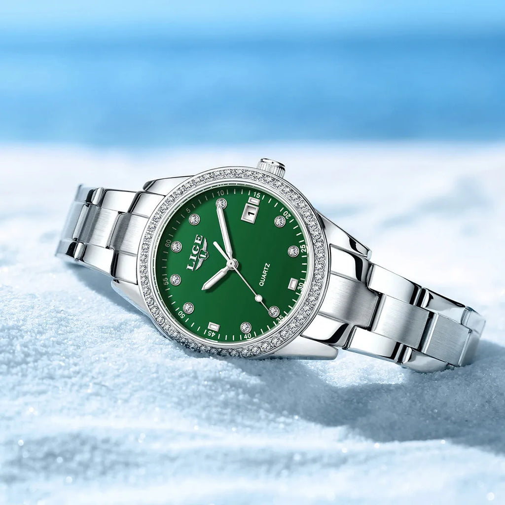 Silver fashion watch with diamond-encrusted round dial and luminous hands on a stainless steel strap.