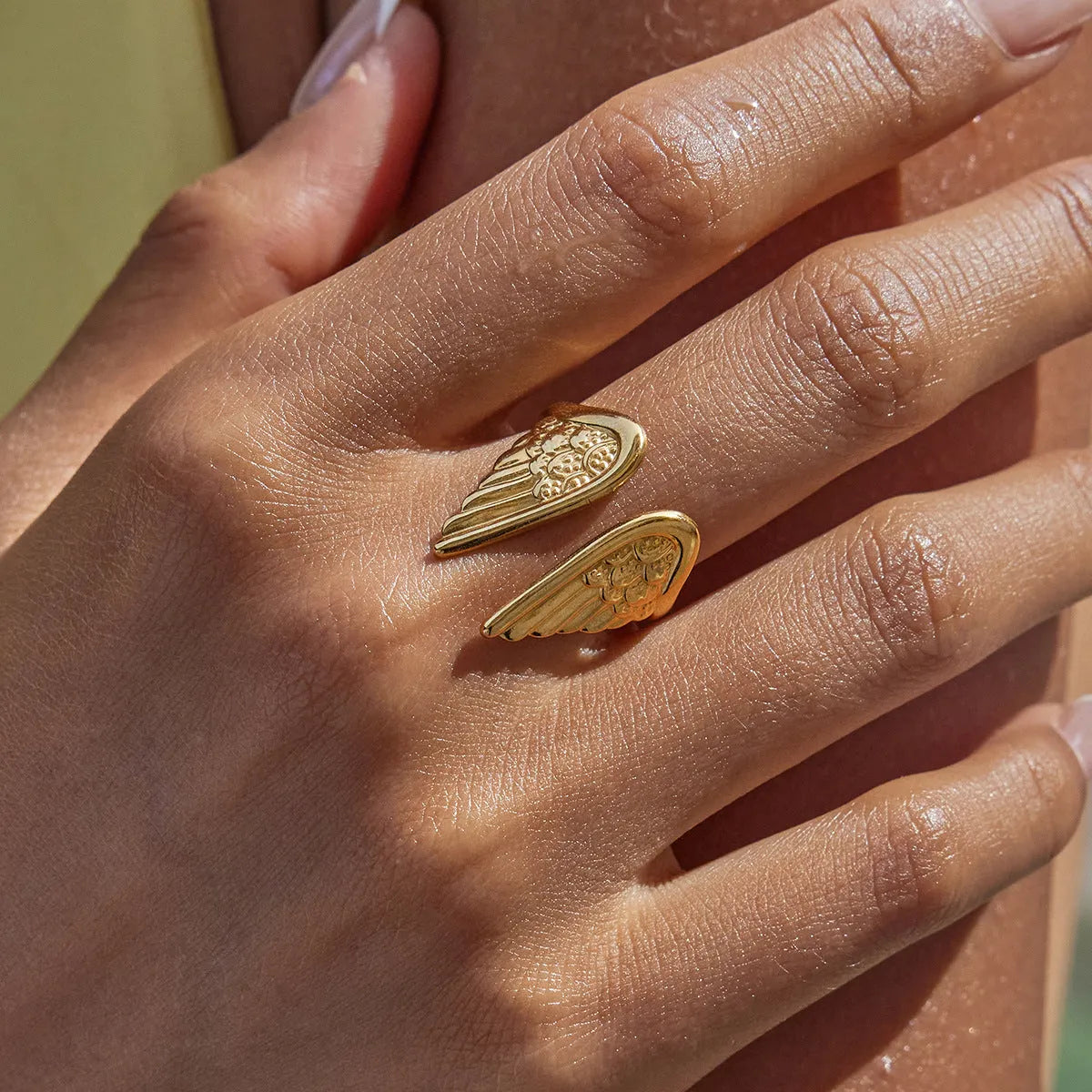 Stainless steel adjustable wings ring in an electroplated colour on a hand.