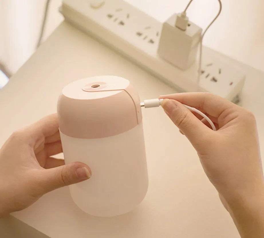 White cylindrical mini humidifier with USB cable on wooden desk