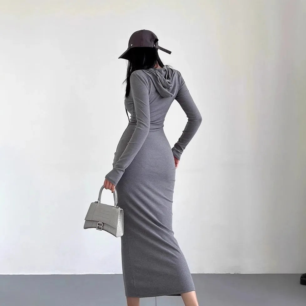 A woman wearing a light grey hooded long sleeve sheath dress with a high waist.