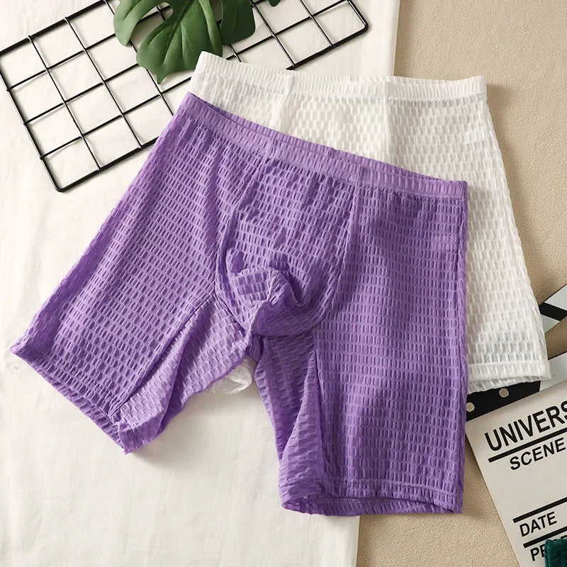 Men's lace boxer underwear in a lengthened hip lifting design on a solid colour background.
