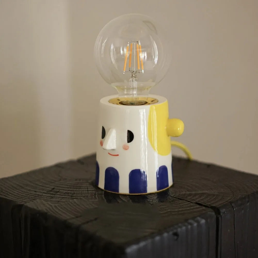 Handmade ceramic bedside lamp with ball-shaped headlight design on wooden surface