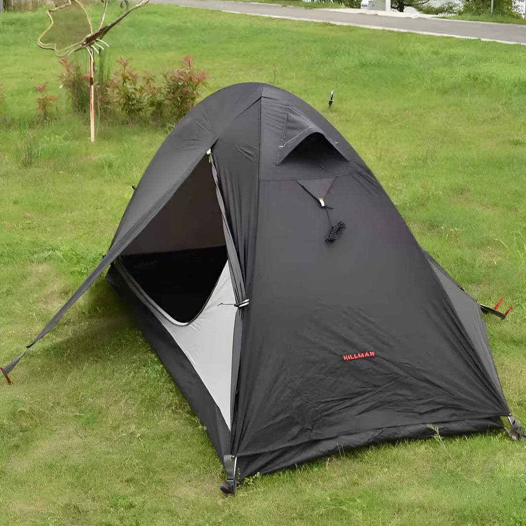 Red single person dome tent with aluminium poles pitched outdoors, showing double-layer construction.