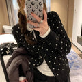 Grey dot patterned women's knitted cardigan with crochet flower detail on a hanger.