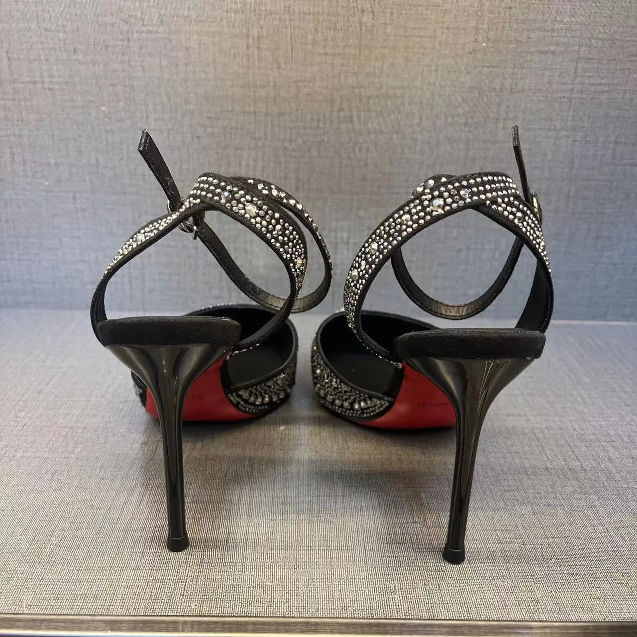 Black women's hollow high heels with pointed toe, stiletto heel, and red sole on a plain background.