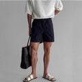 Man wearing loose-fit black cotton sports shorts on a summer day.