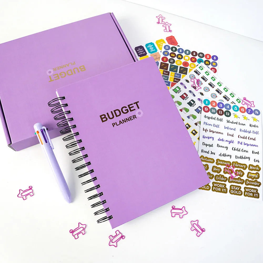 Purple coil-bound financial planning notebook with budget stickers and paper clips on A5 page