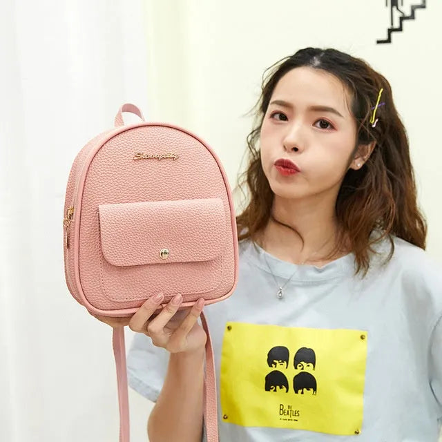 Small black women's PU backpack purse with a zipper, shown with a mobile phone for scale.