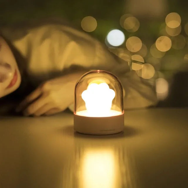 Pink cat paw shaped USB rechargeable night light with musical box function on wooden desktop