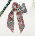 Long ribbon cloth hair ring in spring dark green with floral pattern, shown wrapped as ponytail holder