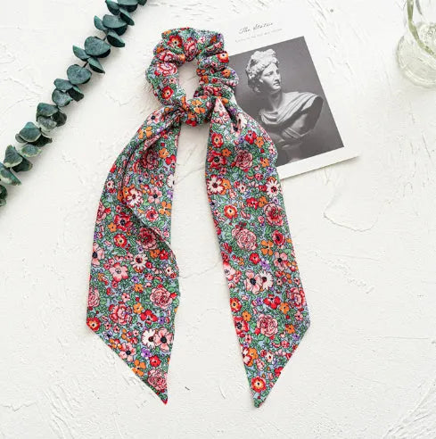 Long ribbon cloth hair ring in spring dark green with floral pattern, shown wrapped as ponytail holder