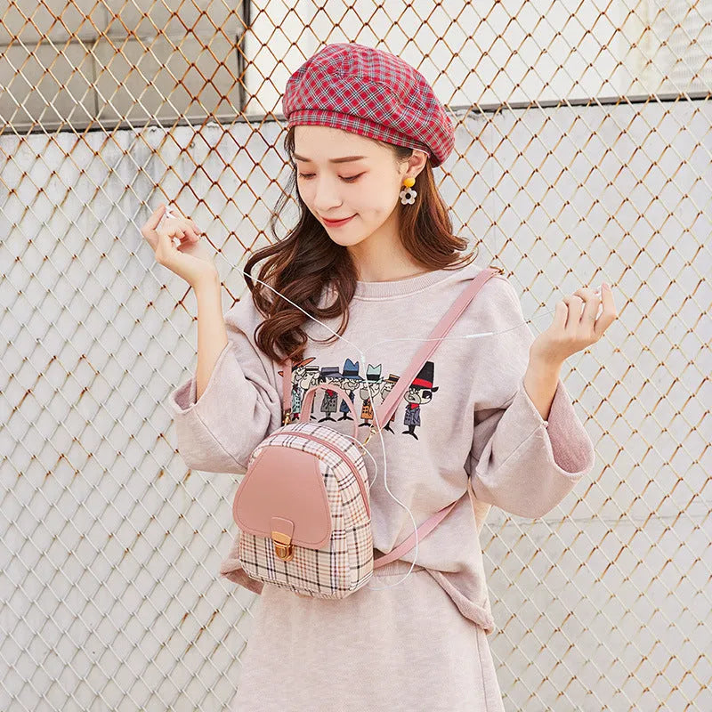 A black diagonal one-shoulder phone bag made from PU fabric, shown being carried by hand.