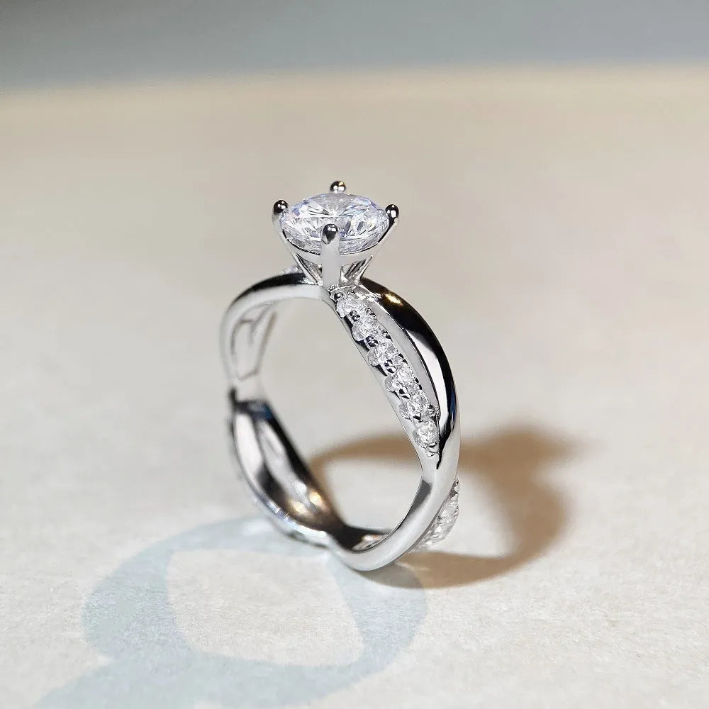Silver geometric cross ring with a 1 karat moissanite stone and twisted band.