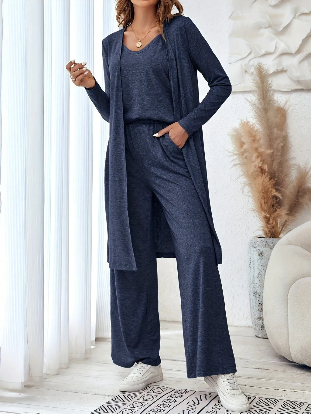 Blue women's three-piece trouser suit set with long cardigan on a hanger.