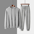 Men's light grey hooded cashmere sweatshirt and matching trousers laid flat as a complete casual set.