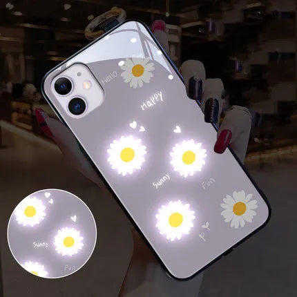 White and purple luminous iPhone cases with painted daisies and voice-activated colour lights on a table.
