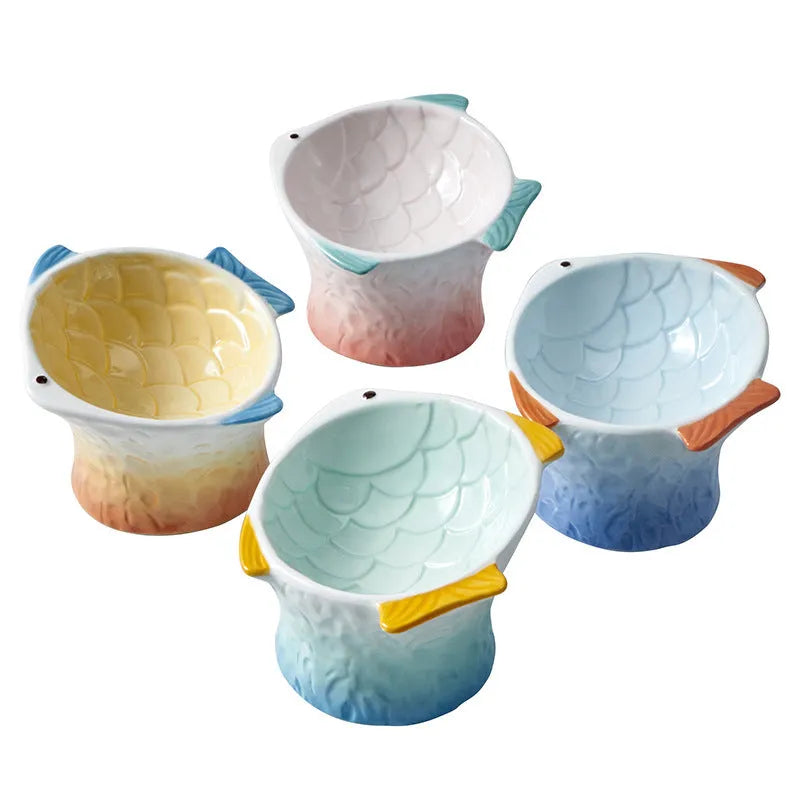 Set of blue, green, pink, and yellow ceramic fish shaped cat bowls with a tilted design.