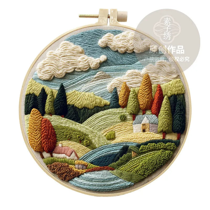 Landscape embroidery DIY kit with cotton fabric, printed pattern, embroidery frame, needles, and thread on wooden surface
