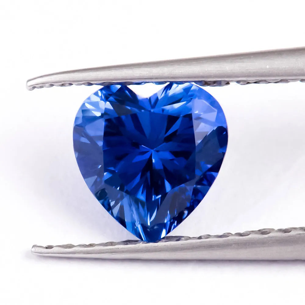 Royal blue cut gemstone in a heart shape on a plain background.