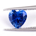 Royal blue cut gemstone in a heart shape on a plain background.