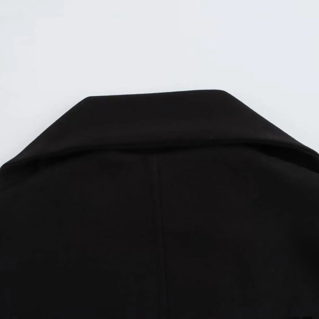 Women's long black polyester overcoat with a gray artificial fur collar, showing street fashion style and front pockets.