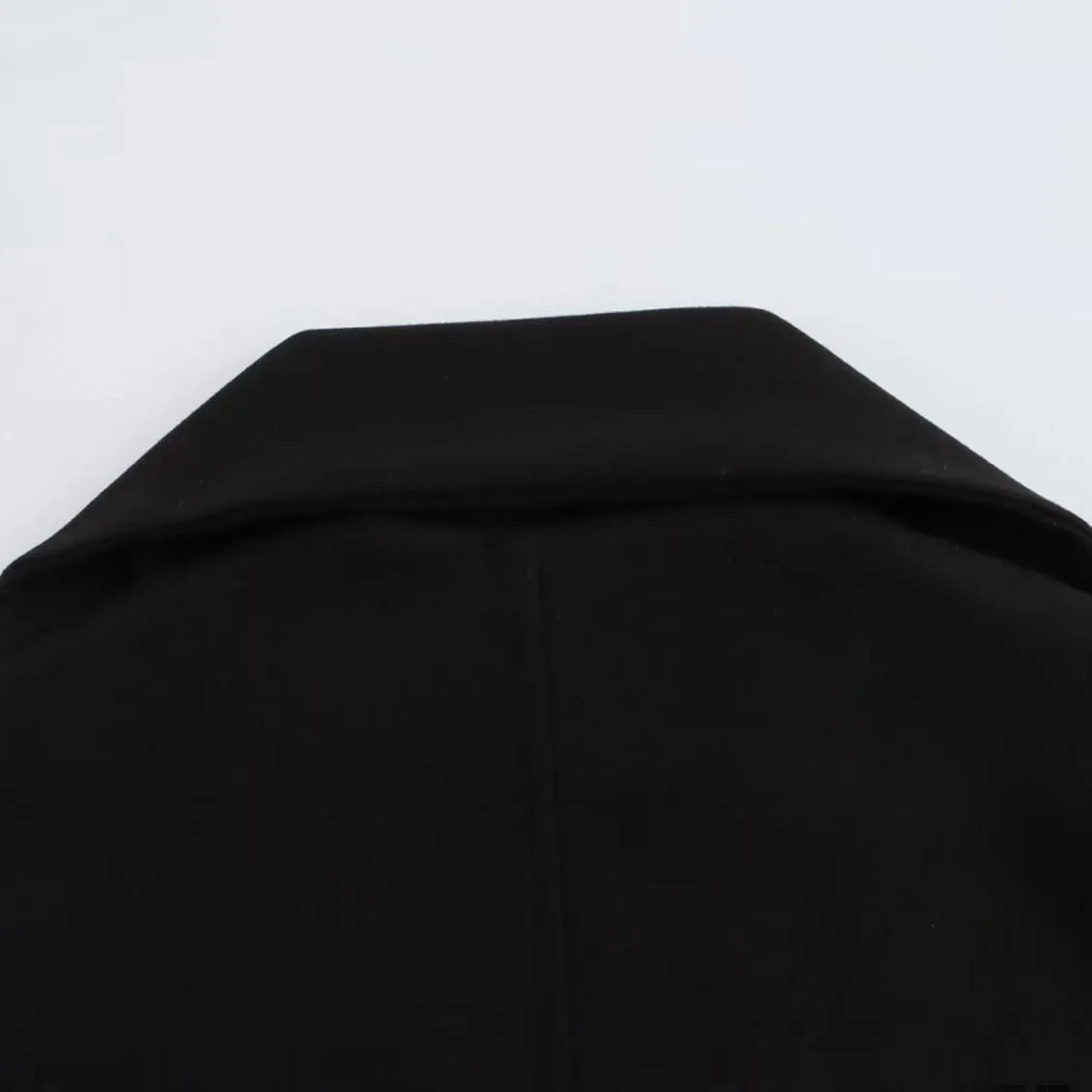Women's long black polyester overcoat with a gray artificial fur collar, showing street fashion style and front pockets.