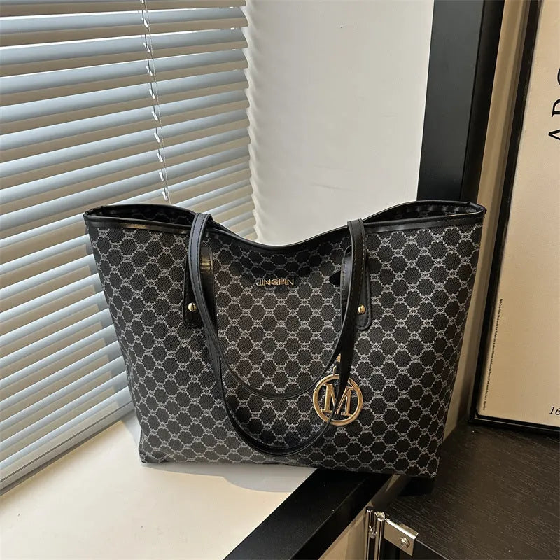 Women's black PU leather shoulder bag with sewing thread detail on a table.