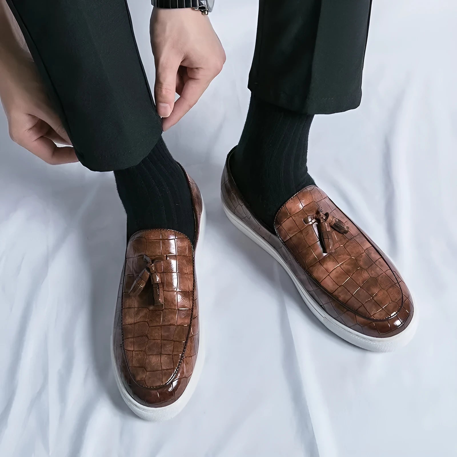 Men's black tassel detail slip-on sneakers with a round toe and rubber sole.
