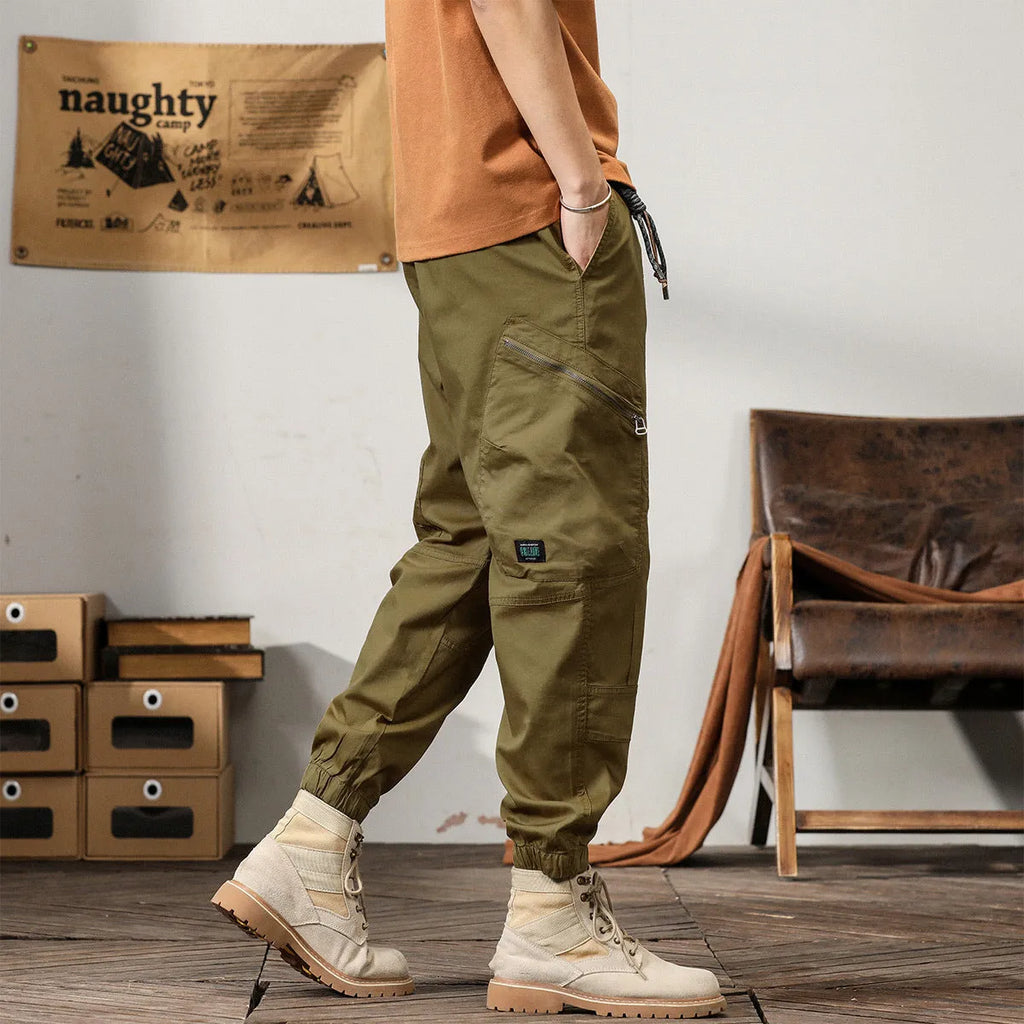 Men's loose cotton harem pants in khaki with a tapered ankle opening and zip fly.
