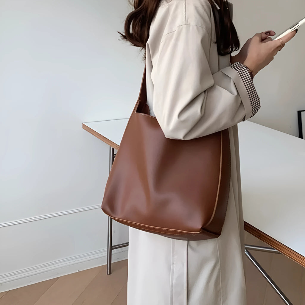 Two women's fashion shoulder bags: black with ribbon and brown with packet designs showing swing thread details