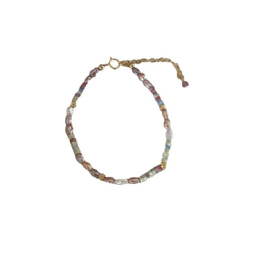 Close-up of a women's mini bracelet with irregular natural pearls set in 14K gilded purple silver, shown with its matching necklace.