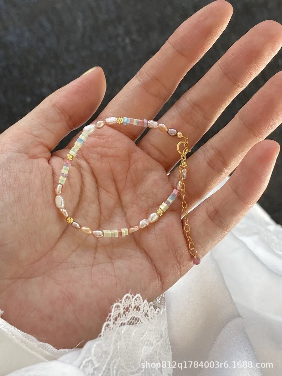 Close-up of a women's mini bracelet with irregular natural pearls set in 14K gilded purple silver, shown with its matching necklace.