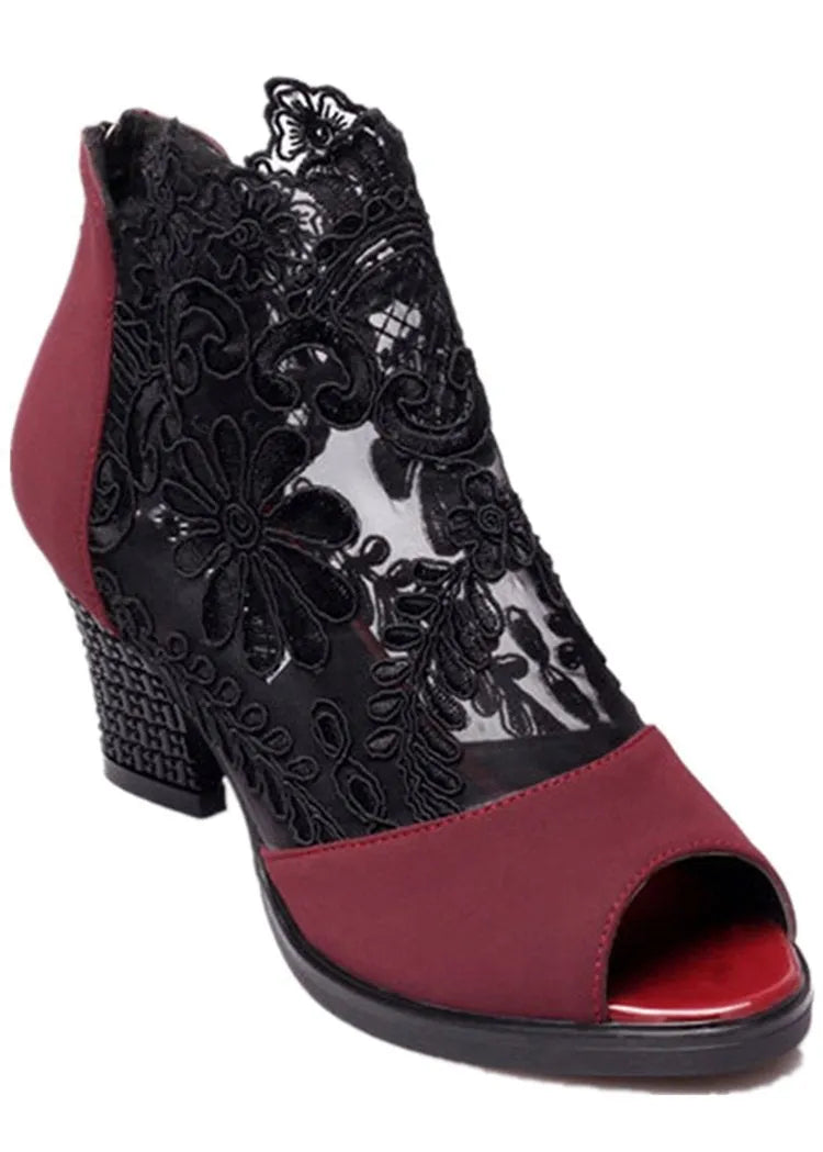 Black women's gladiator sandals with lace upper, square high heel, and side zip closure on a foot.