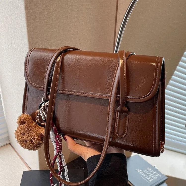 Brown women's PU leather crossbody shoulder bag with pendant, showing front view and adjustable double straps.