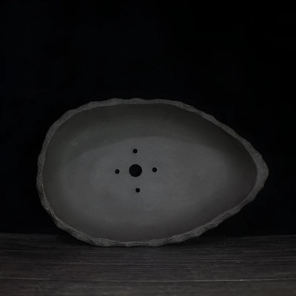 Handmade purple clay flower pot with sculptural shape on wooden floor