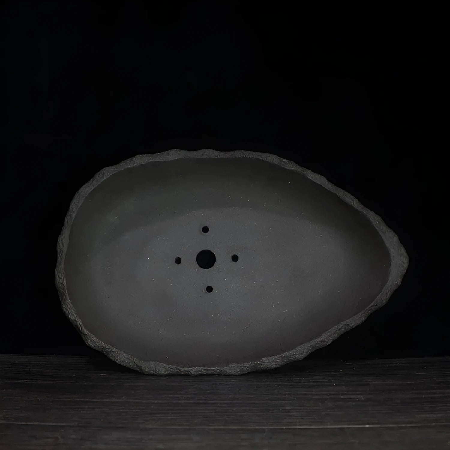 Handmade purple clay flower pot with sculptural shape on wooden floor
