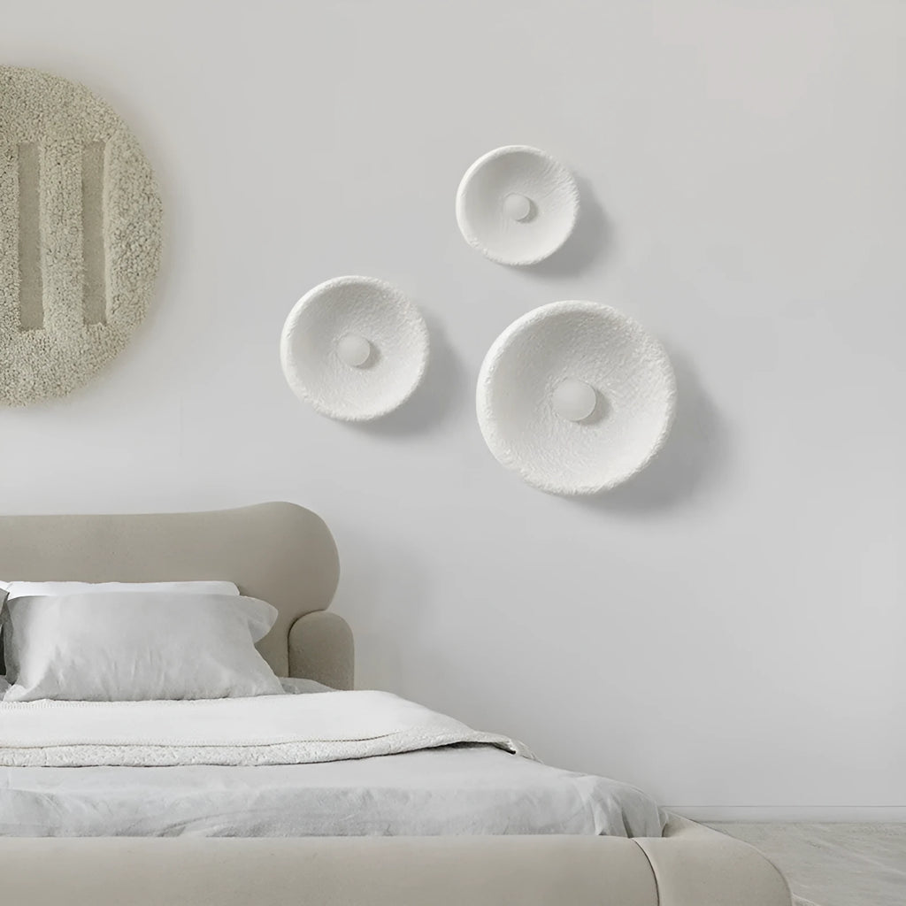 Japanese modern simple wall lamp with white resin shade in three size options on a plain wall.