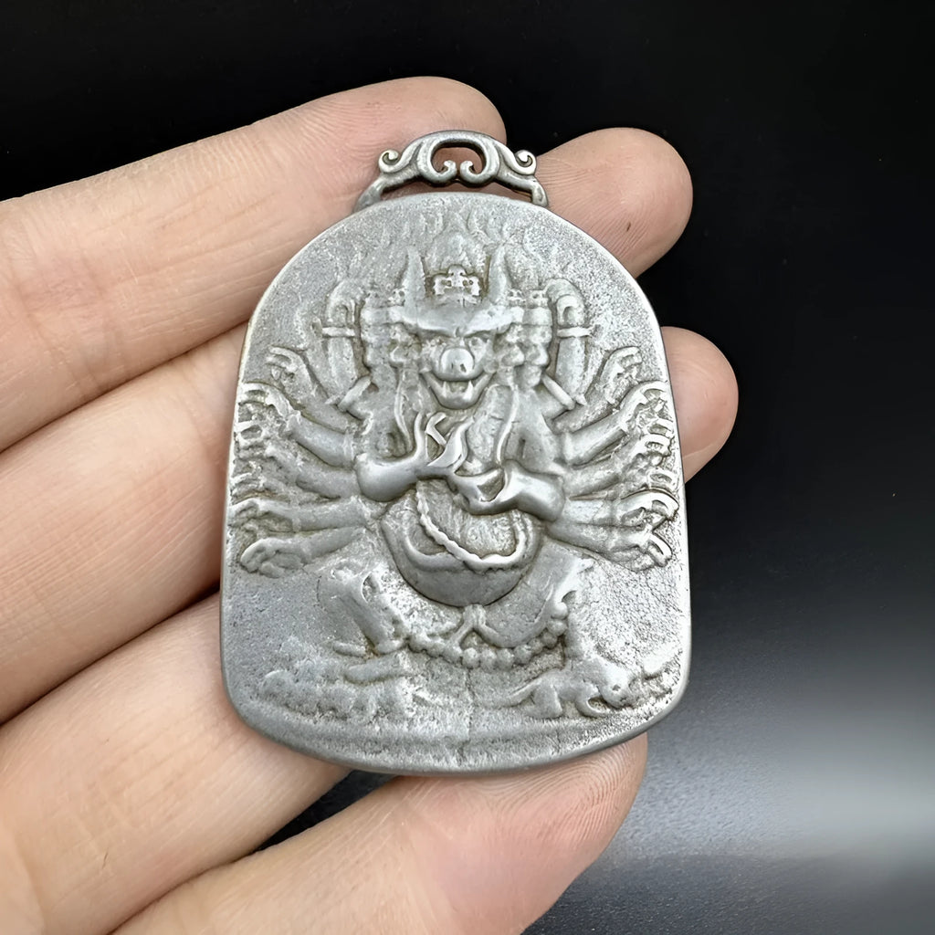 Close-up of an antique iron pendant depicting the Aryaacalanatha Yamantaka icon in a Chinese geometric style.