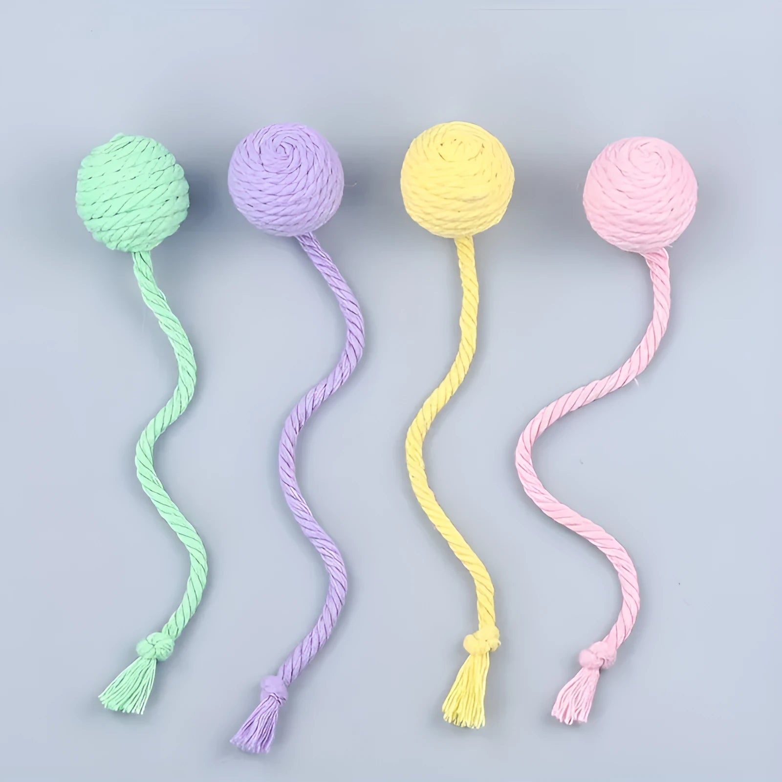 Colourful cat toy ball with an attached rope and an internal bell, shown in green, pink, purple and yellow.