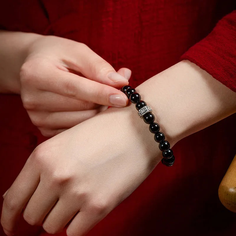 Old Pit Obsidian 8mm bracelet with detailed metal zodiac animal and Buddhist bodhisattva charms.