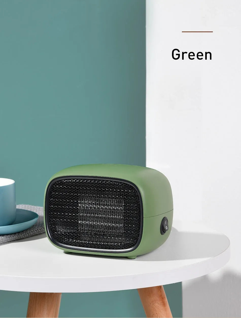 Mini green desktop heater with metal grille showing compact size on a wooden desk