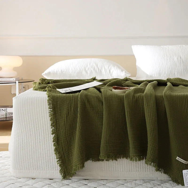 Four-layer gauze cotton blanket with tassel trim in navy blue colour laid flat.