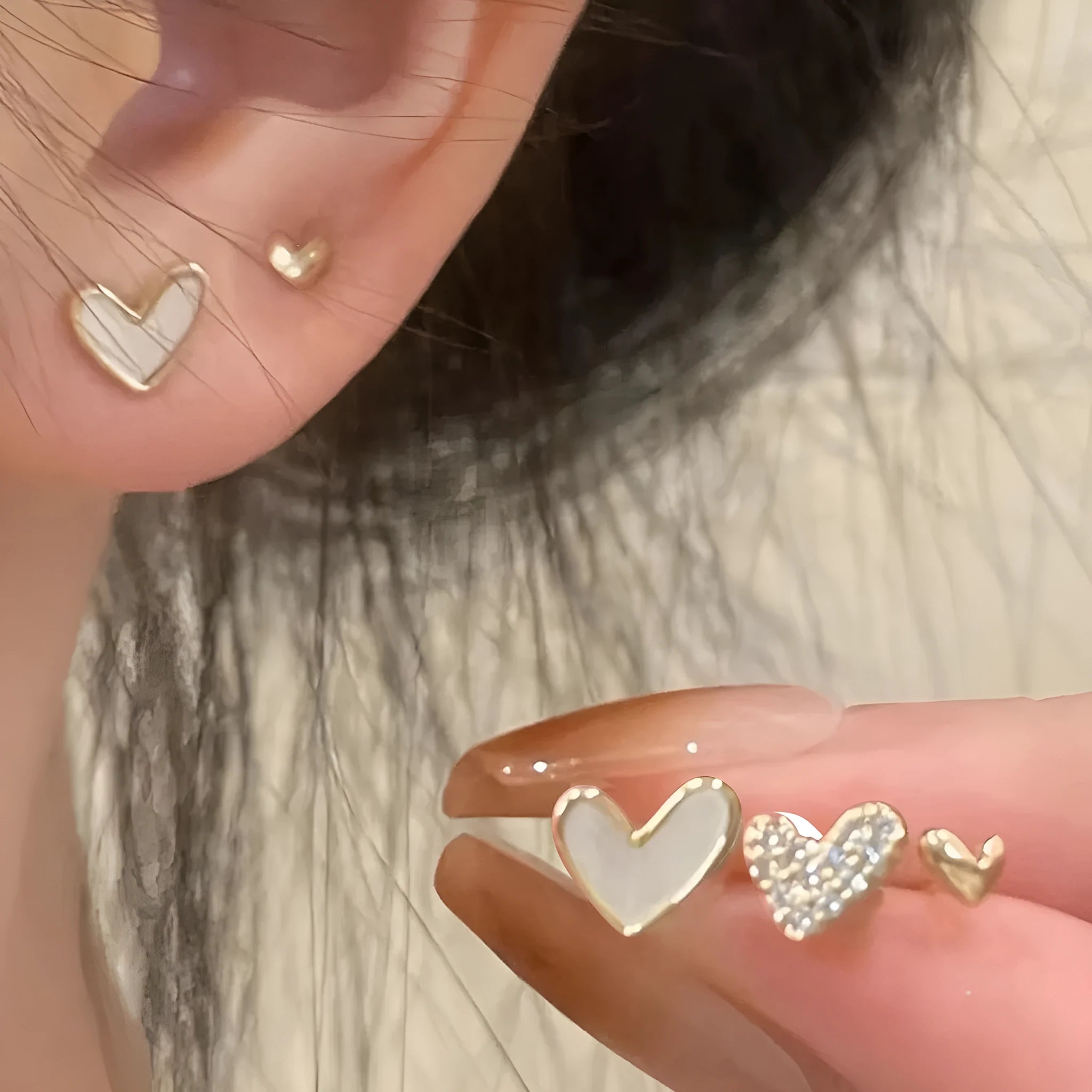 Three pairs of heart-shaped girly earrings in gold, black, black and white, and pink colours