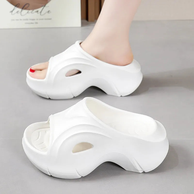 Women's thick-soled EVA slippers in rose red colour on a sandy beach background.