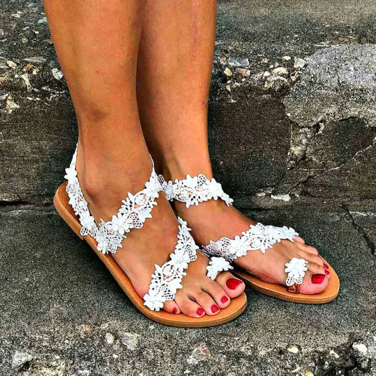 White women's flat sandals with rhinestone and floral decoration on the strap.