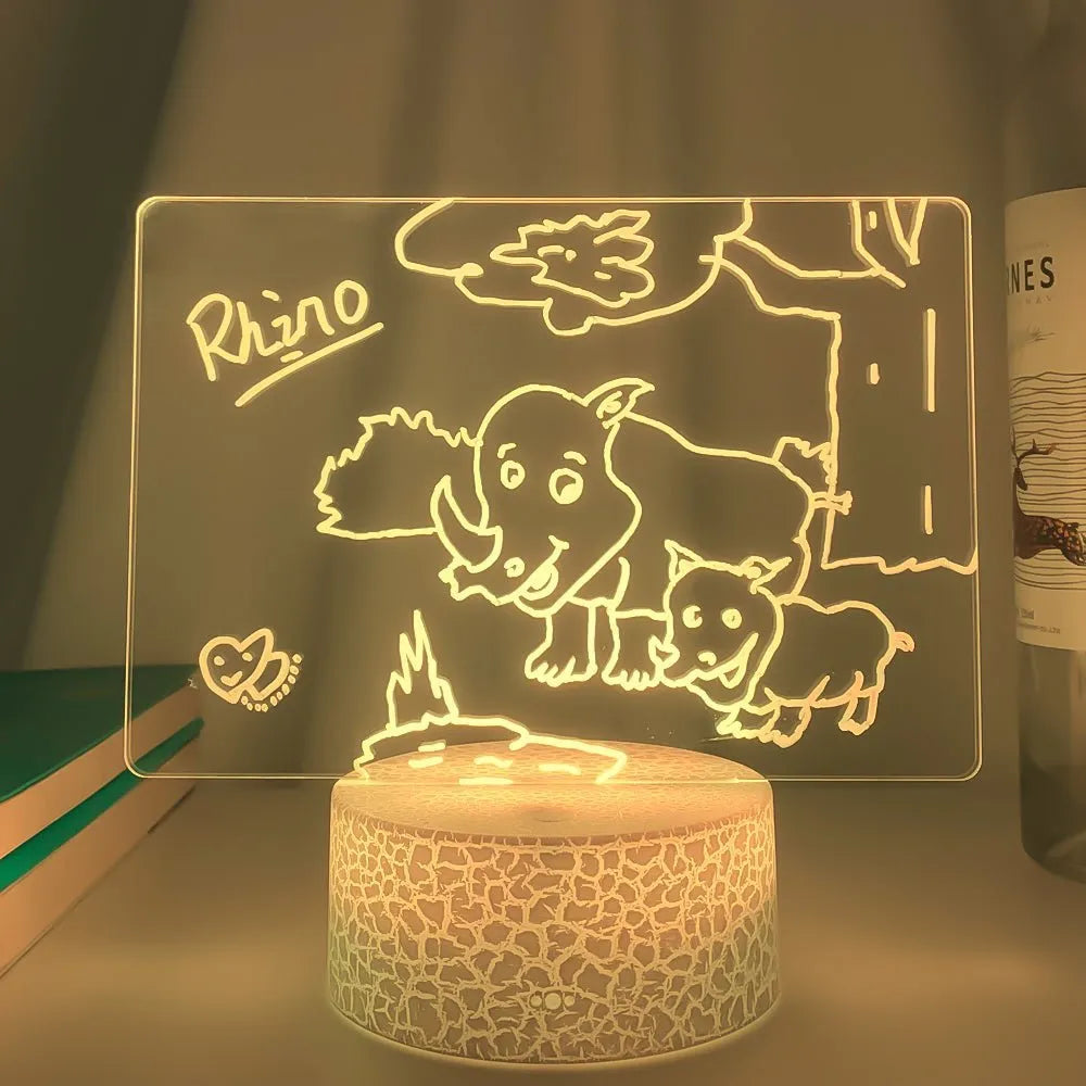 3D acrylic message board LED lamp lit up on a desk with remote control and marker pen.