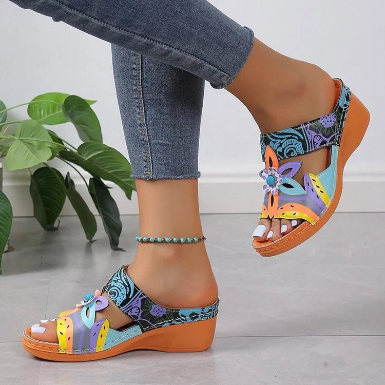Ethnic patterned cowhide slippers in orange with coloured slopes and a totem design on a rubber sole.