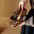 Women's black square toe stiletto heel ankle-strap shoes with horse hair upper on a neutral background.