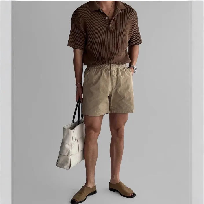 Man wearing loose-fit black cotton sports shorts on a summer day.